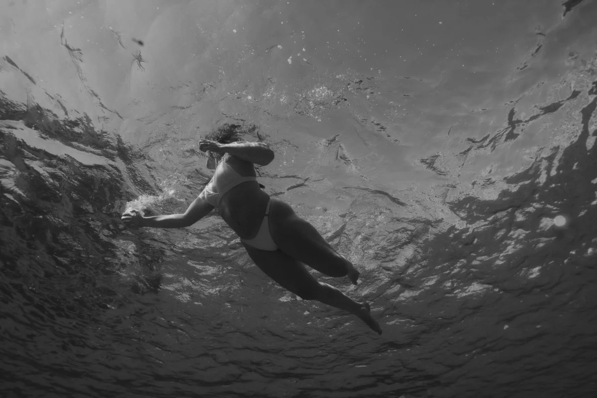artistieke zwart-wit foto van een vrouw die in het water drijft en rust en vrijheid uitstraalt.