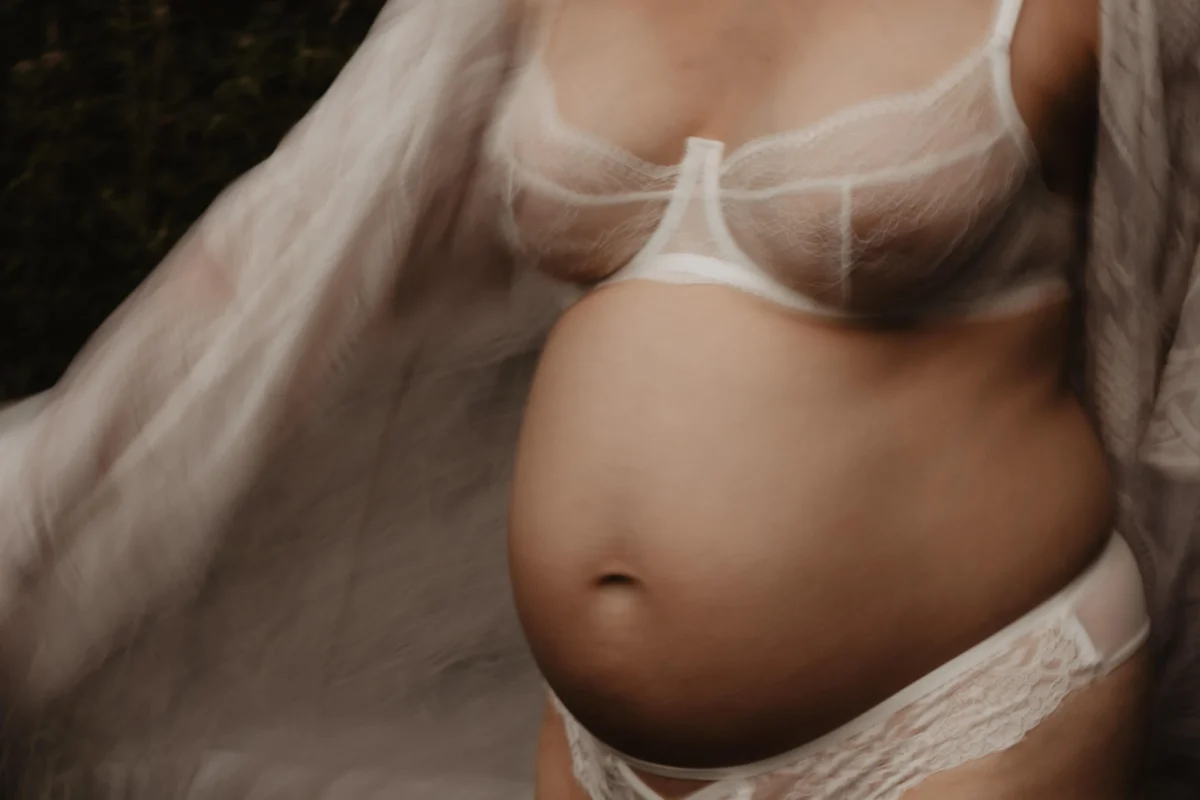 vintage bewogen close up van buik en borsten van zwangere vrouw met witte lingerie aan