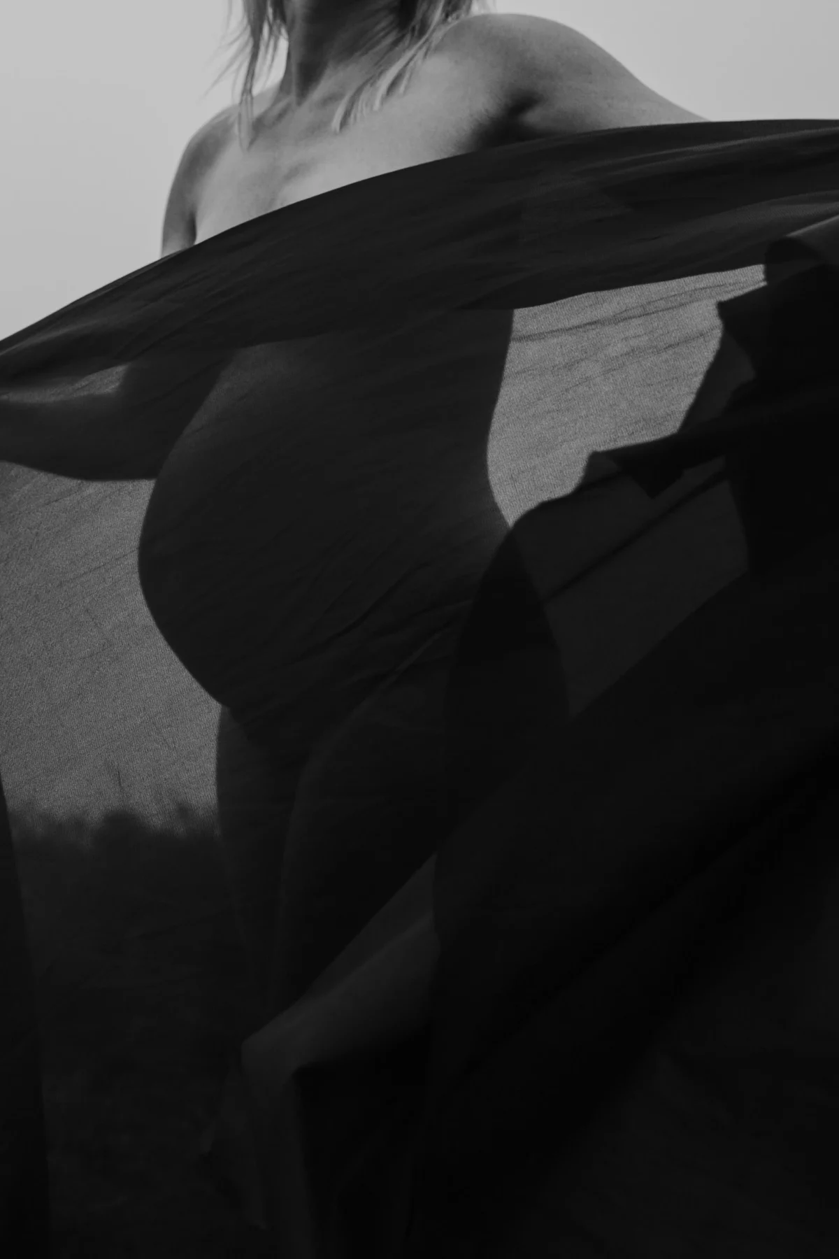 artistiek beeld van zwangere vrouw die een doorzichtige zwarte doek voor haar buik houdt