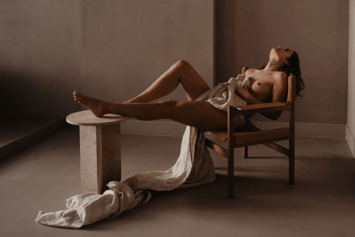 Boudoir-shoot-binnen-vrouw-met-benen-op-tafel-en-laken-over-torso