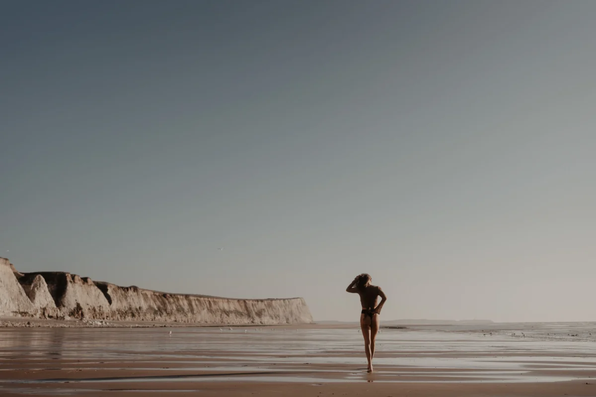 vrouw in elegante pose op desolaat strand in Frankrijk op een zonnige dag met een overbelicht effect.