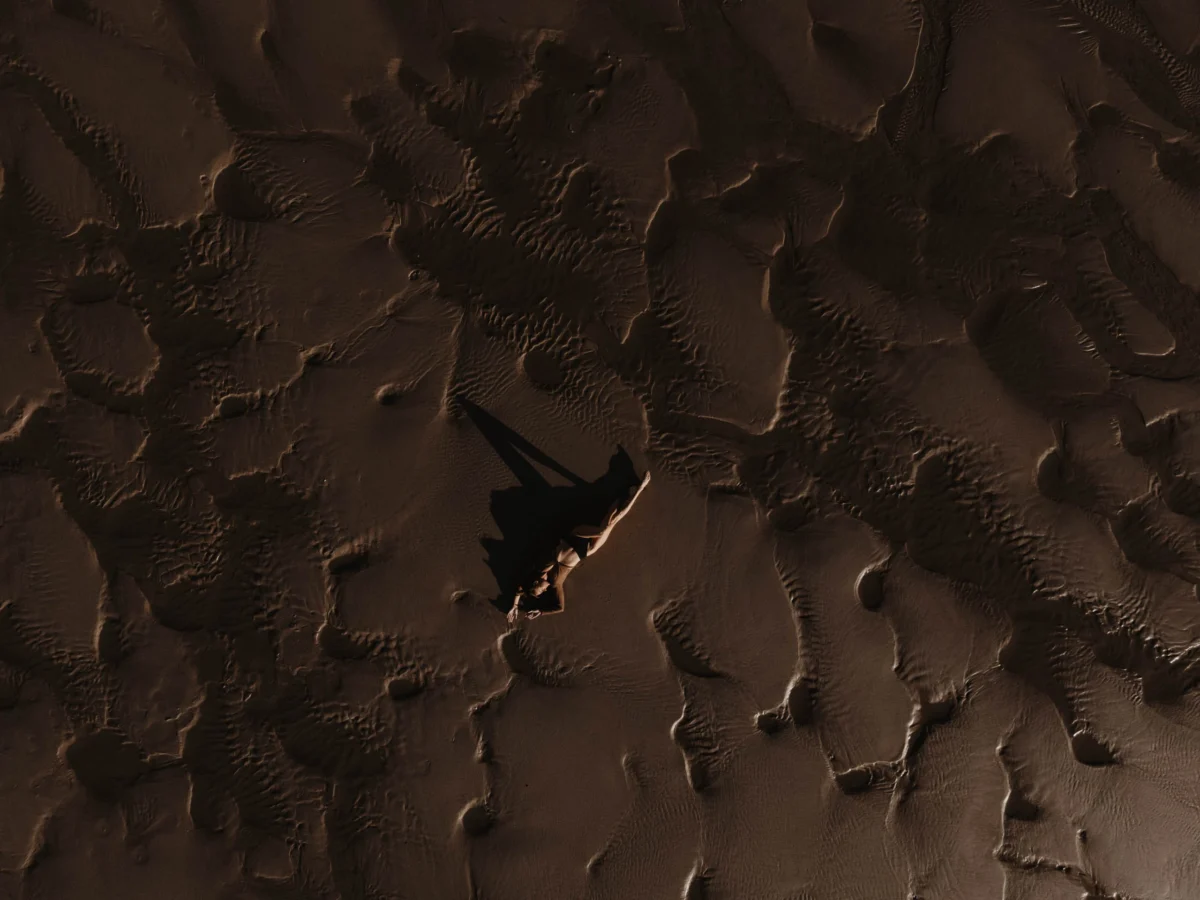 Clair obscuur beeld, zoals Rembrandt dat deed van vrouw op het strand maar met heel weinig licht dus alles is heel donker en je ziet goed de textuur van het zand.