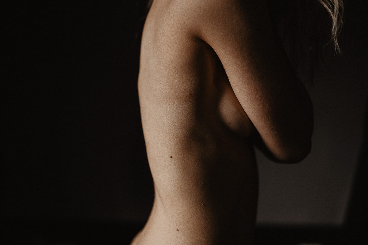 minimalistisch beeld van vrouw met ontbloot bovenlichaam met veel schaduw