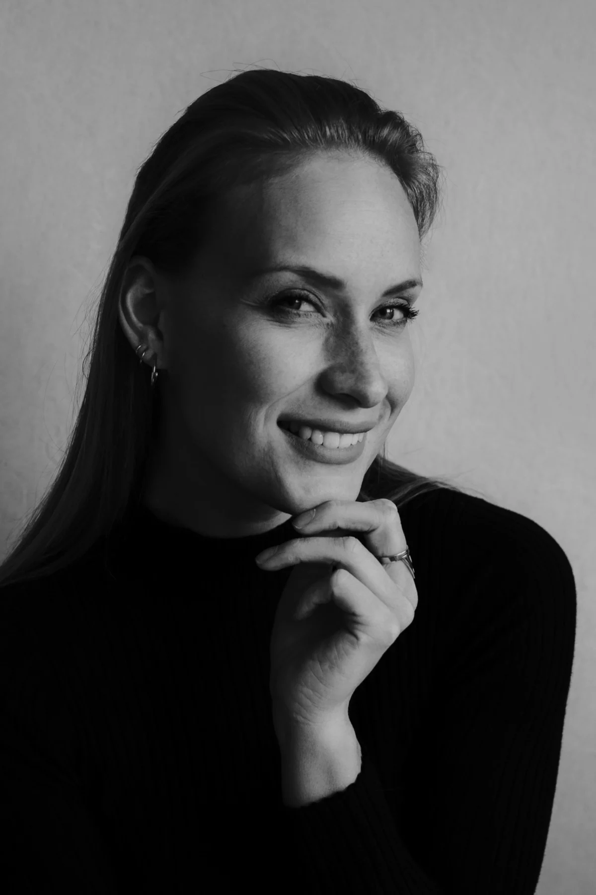 Angela portret lacht in camera, zwart-wit, heeft hand onder kin